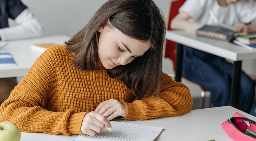 diáklány iskolapadban ír